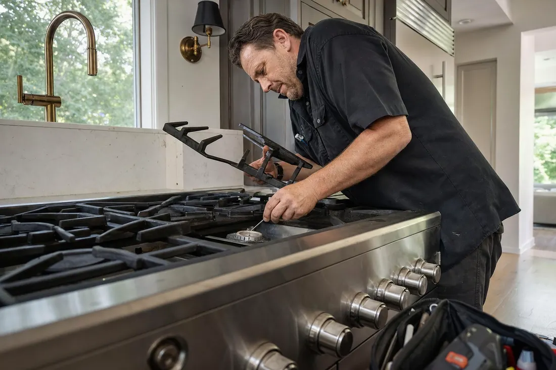 Technician checking a sealed burner on a professional gas range, one grate lifted, the sealed burner in frame - Thermador appliance repair